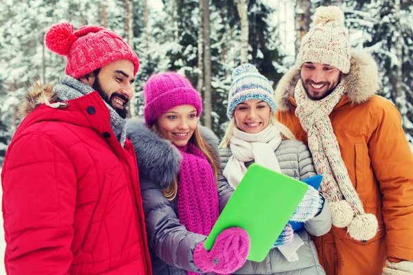 Lachende vrienden met tablet pc in winter forest — Stockfoto