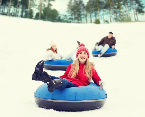 Group of happy friends sliding down on snow tubes — Stock Photo, Image