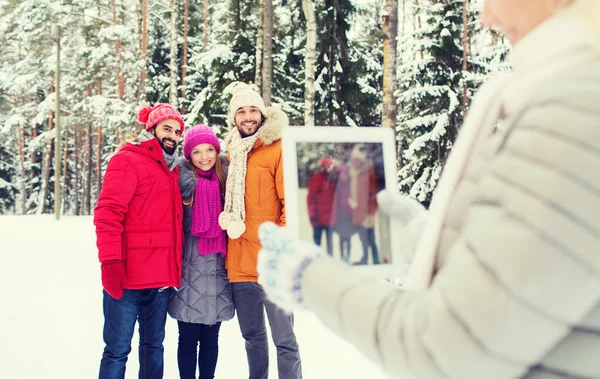 Lachende vrienden met tablet pc in winter forest — Stockfoto