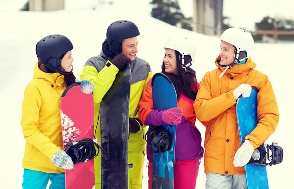 Amigos felices en cascos con tablas de snowboard hablando —  Fotos de Stock