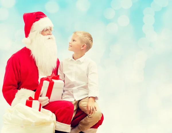 Niño sonriente con santa claus y regalos — Foto de Stock