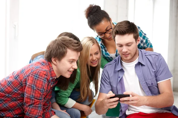 Gruppo di studenti felici con smartphone a scuola — Foto Stock