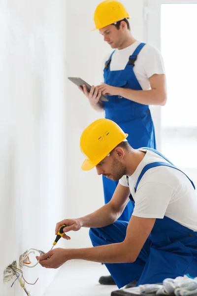 Construtores com tablet pc e fixação de fiação dentro de casa — Fotografia de Stock