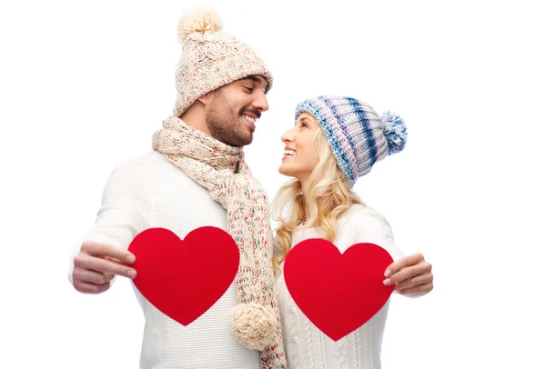 Smiling couple in winter clothes with red hearts — Stock Photo, Image