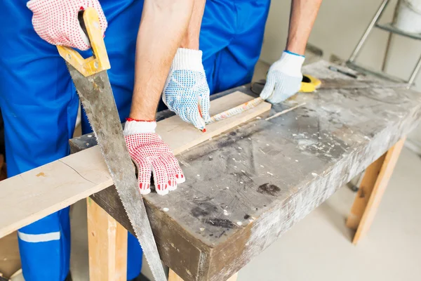 Close up of builders with arm saw sawing board — Stock Photo, Image