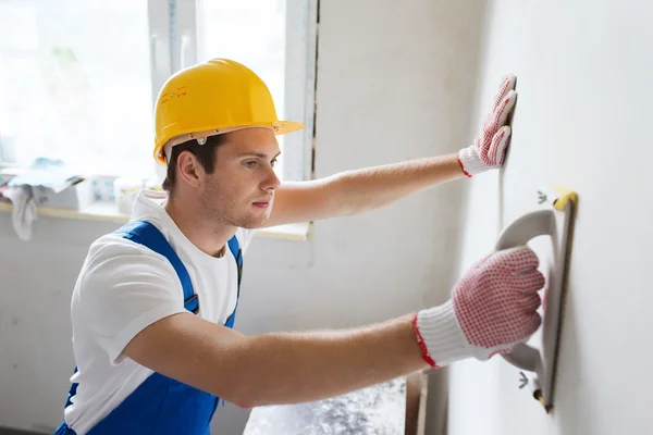 Construtor sorrindo com ferramenta de moagem dentro de casa — Fotografia de Stock