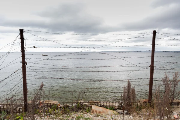 Ακίδιο σύρμα περίφραξης γκρίζος ουρανός και θάλασσα — Φωτογραφία Αρχείου