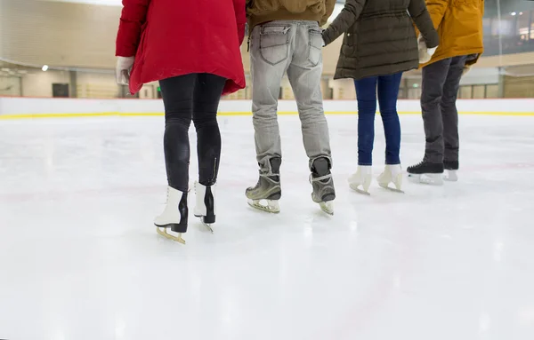 Primo piano di amici felici pattinaggio su pista di ghiaccio — Foto Stock