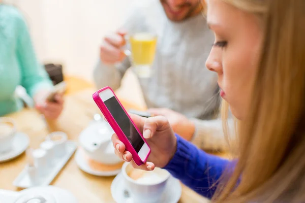 Woman with friends texting on smartphone at cafe — Stockfoto