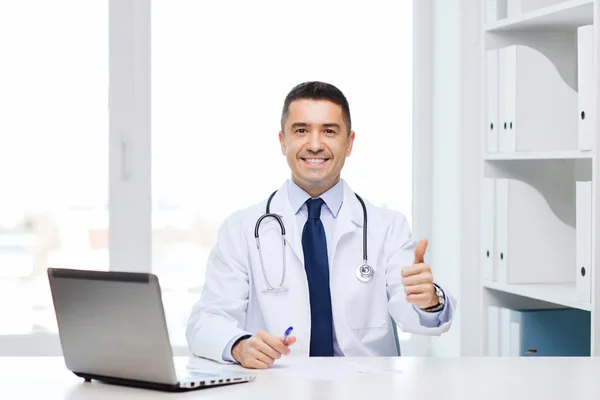 Smiling doctor showing thumbs up in medical office — Stockfoto