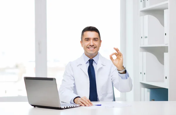 Lächelnder Arzt mit Laptop im Büro — Stockfoto