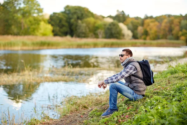 Hombre con mochila descansando en la orilla del río —  Fotos de Stock