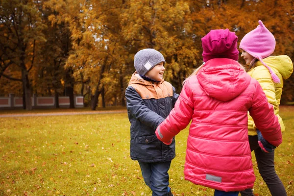 Crianças de mãos dadas e brincando no parque de outono — Fotografia de Stock