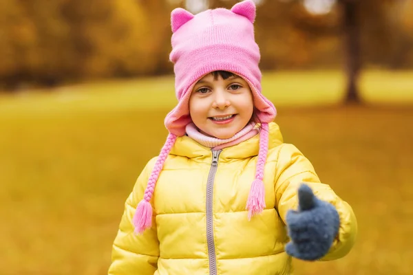 Happy little girl showing thumbs up outdoors — Stok fotoğraf