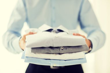 close up of businessman holding folded shirts clipart
