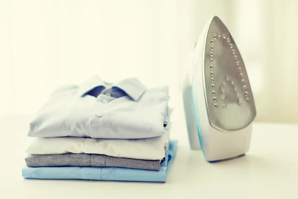 Close up of iron and clothes on table at home — Stock Photo, Image