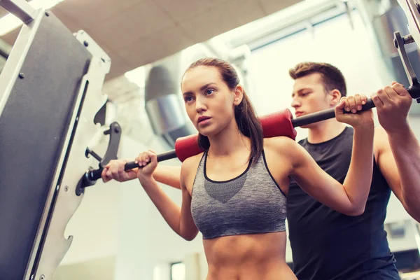 Hombre y mujer con los músculos de flexión de la barra en el gimnasio — Foto de Stock