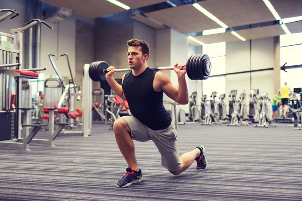 Young man flexing muscles with barbell in gym — Stock Photo, Image