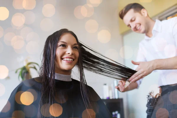 Счастливая женщина со стилистом стрижет волосы в салоне — стоковое фото