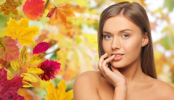 Krásná mladá žena tvář nad podzimní listí — Stock fotografie