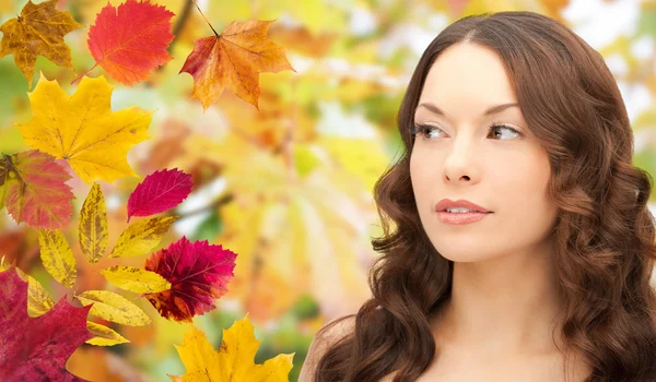 Hermosa cara de mujer joven sobre hojas de otoño —  Fotos de Stock