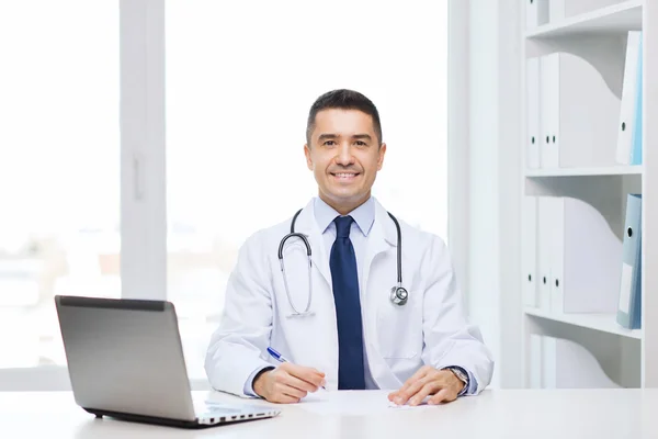 Lächelnder Arzt mit Laptop in Arztpraxis — Stockfoto