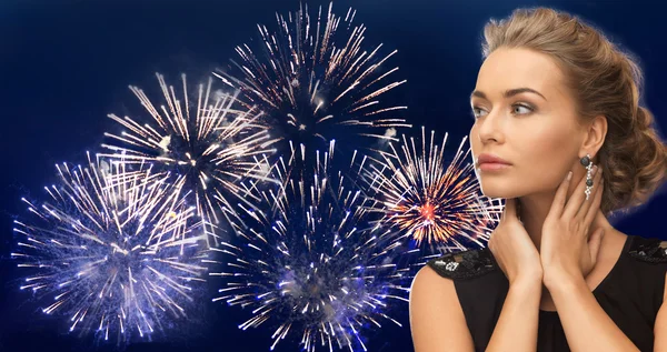 Beautiful woman wearing earrings over firework Royaltyfria Stockbilder