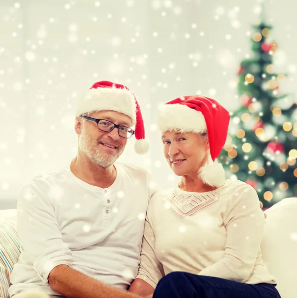 Feliz casal sênior em santa helper chapéus em casa — Fotografia de Stock