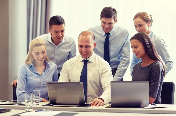 Uomini d'affari sorridenti con computer portatili in ufficio — Foto Stock