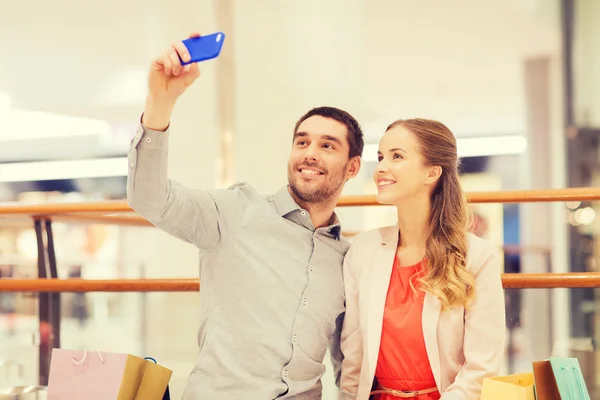 Gelukkige paar met smartphone nemen selfie in winkelcentrum — Stockfoto