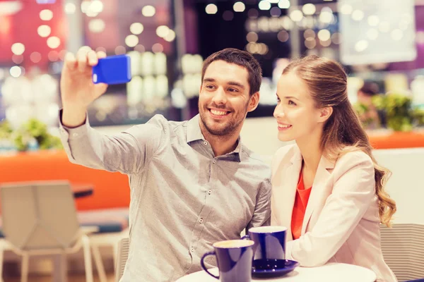 Happy couple with smartphone taking selfie in mall — Stock Photo, Image