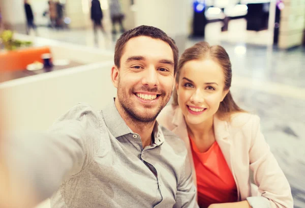 Feliz pareja tomando selfie en centro comercial u oficina —  Fotos de Stock