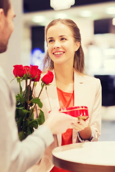 Lyckliga par med present och blommor i gallerian — Stockfoto