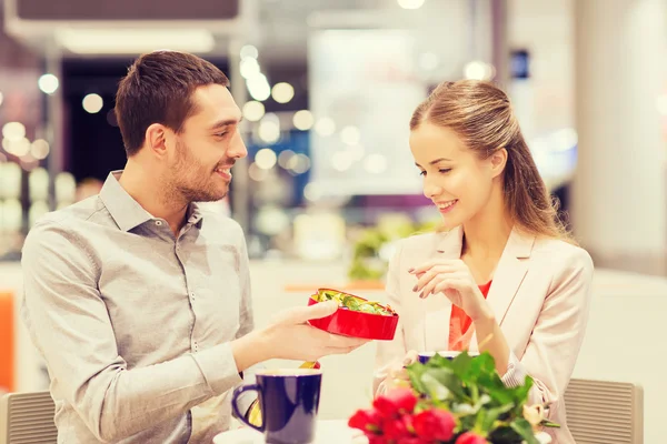 Casal feliz com presente e flores no shopping — Fotografia de Stock