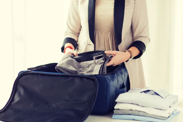 Femme emballant des vêtements masculins formels dans un sac de voyage — Photo