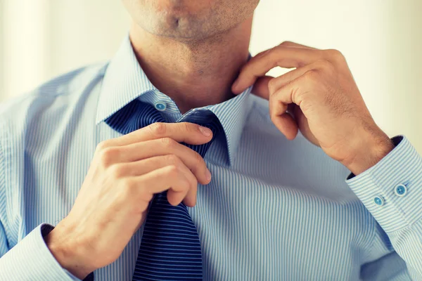 Close up de homem na camisa ajustando gravata no pescoço — Fotografia de Stock