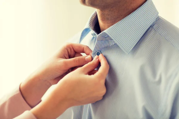 Close up of man and woman fastening shirt buttons — Stock Photo, Image