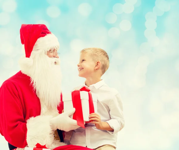 Smiling little boy with santa claus and gifts — Stock Photo, Image