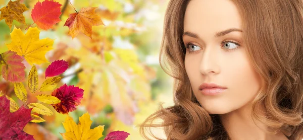 Bella giovane donna faccia su foglie di autunno — Foto Stock
