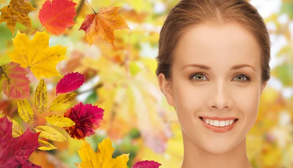 Mooie jonge vrouw gezicht over Herfstbladeren — Stockfoto