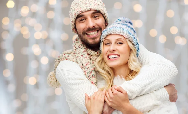 Happy couple in winter clothes hugging over lights — Stock Fotó