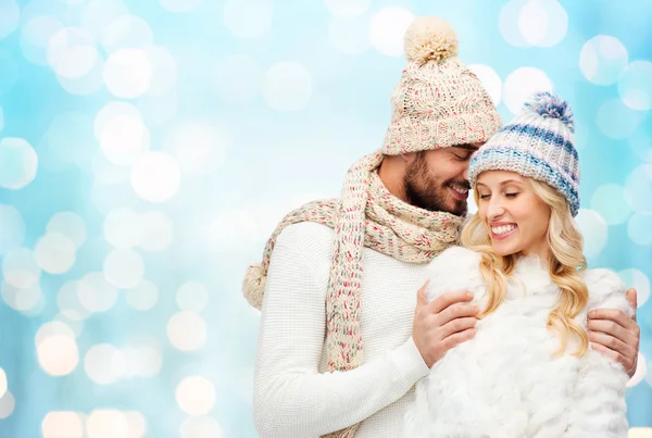 Happy couple in winter clothes hugging over lights — Stock fotografie