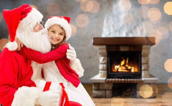 Smiling family with santa claus and gift at home — Stockfoto