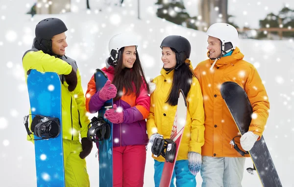 Amigos felices en cascos con tablas de snowboard hablando —  Fotos de Stock