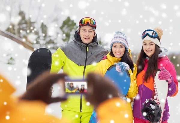Amigos felices con tablas de snowboard y smartphone —  Fotos de Stock