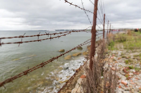 Ogrodzeniem z drutu haczyka szare niebo i morze — Zdjęcie stockowe