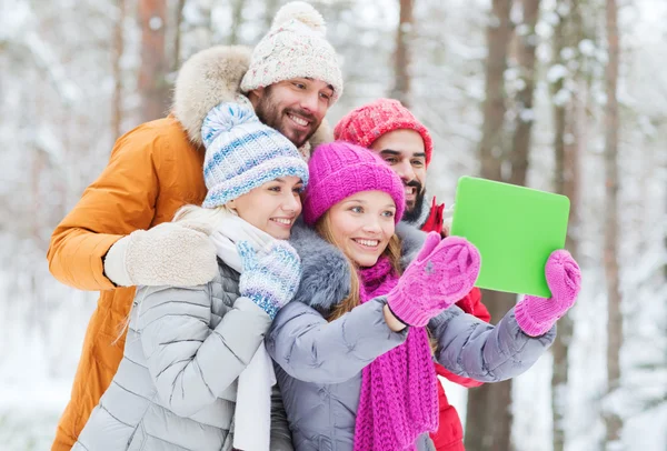 Amigos sorridentes com tablet pc na floresta de inverno — Fotografia de Stock