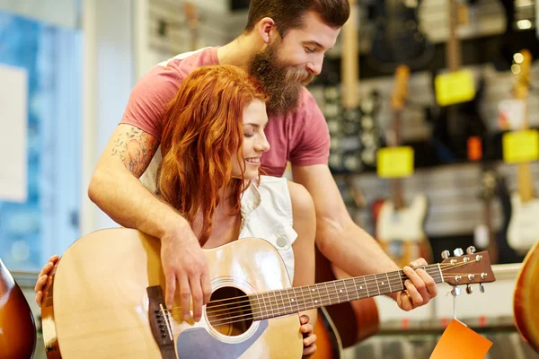 Pareja de músicos con guitarra en tienda de música — Foto de Stock