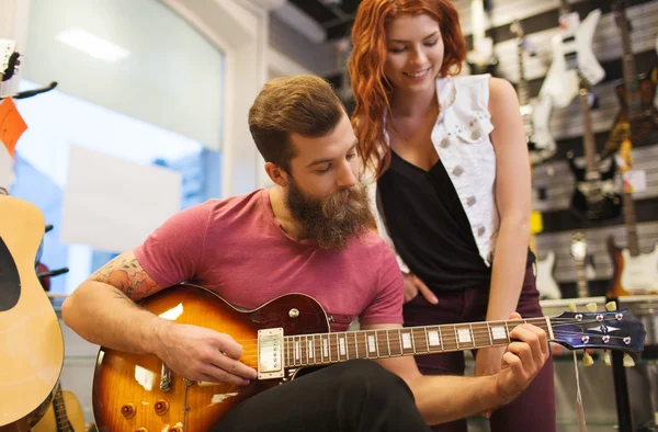 Pareja de músicos con guitarra en tienda de música — Foto de Stock