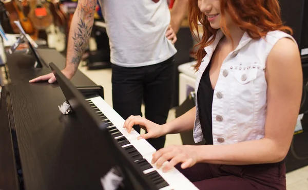 Man and woman playing piano at music store — Stock Photo, Image